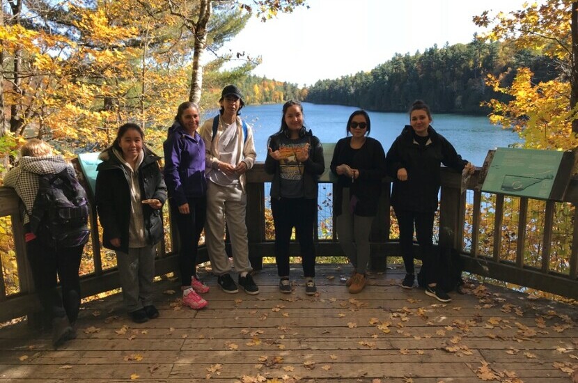 high school students posing in front of a lake in autumn